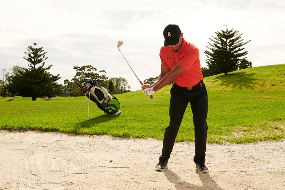 golfer in bunker using sand wedge